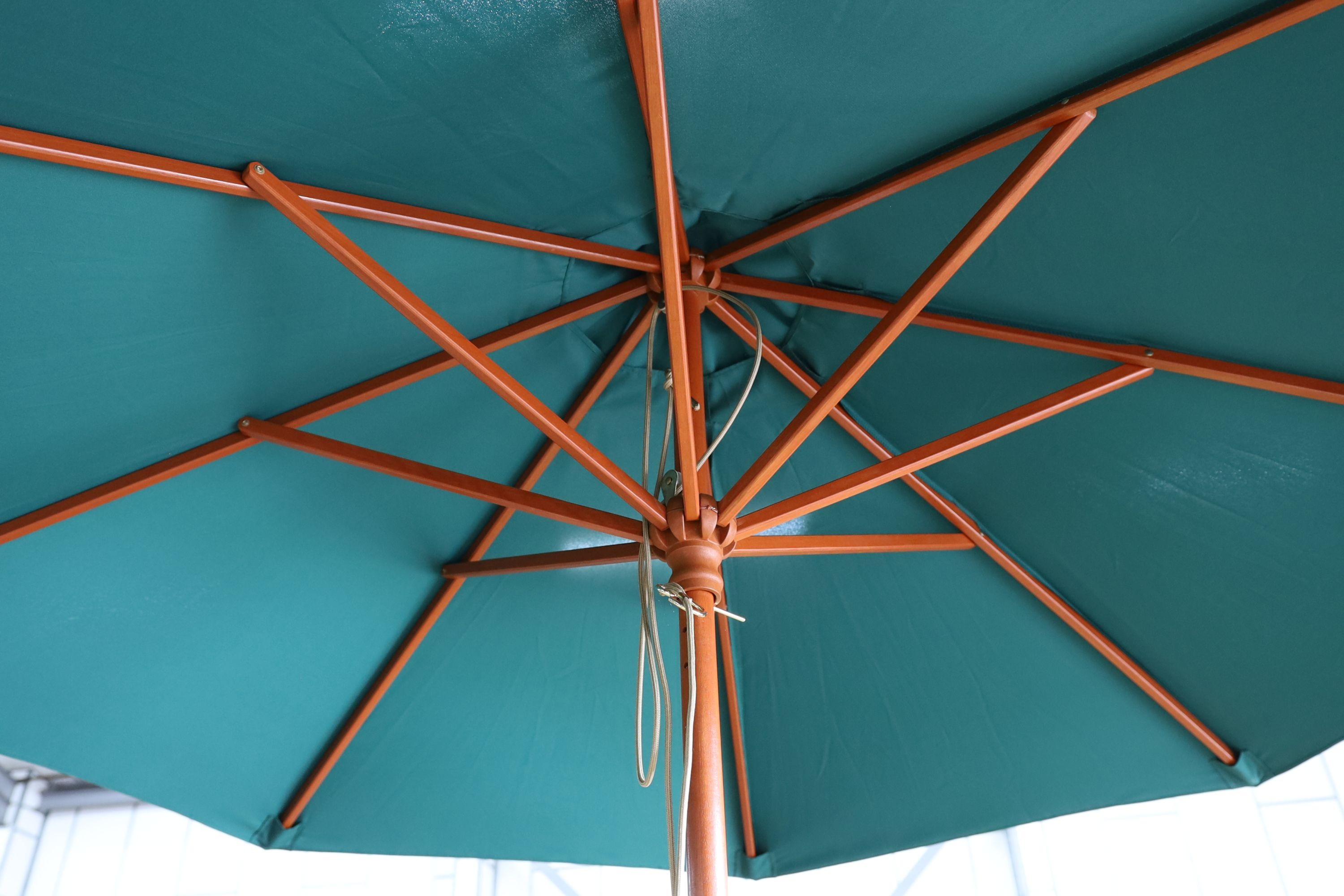 A teak garden set comprising circular table 148 cms diameter height 75 cms with 'Lazy Susan', parasol and waterproof cover and metal base, six folding elbow chairs and seat cushions.